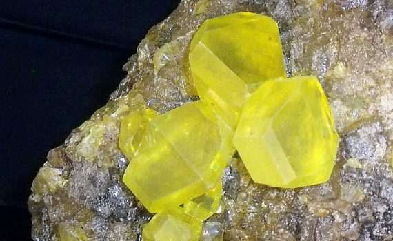 Over time, monoclinic needle crystals spontaneously change shape into rhomboid sulfur crystals.